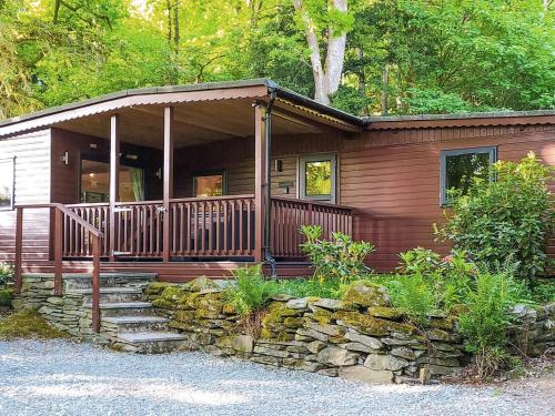a wooden cabin with a porch and a stone wall at Elterwater Neaum Crag in Elterwater