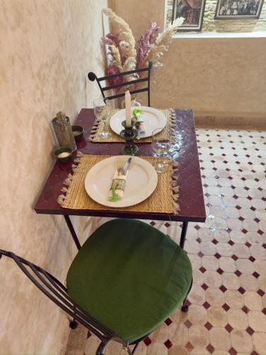 een tafel met een groen bord en een kaars erop bij Riad Al Karama in Marrakesh