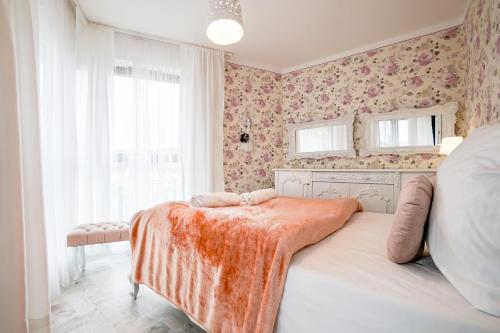 a bedroom with a bed with an orange blanket on it at Horyzont by Baltic Home in Międzyzdroje
