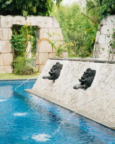 two gargoyles sitting on the side of a swimming pool at Mustika Yogyakarta Resort and Spa in Yogyakarta