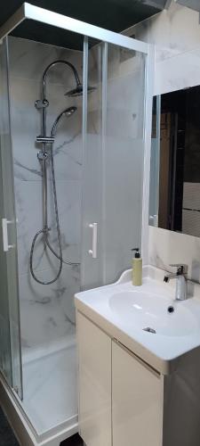 une salle de bain blanche avec une douche et un lavabo dans l'établissement F3 A 400 m du Stade de France JO, à Saint-Denis