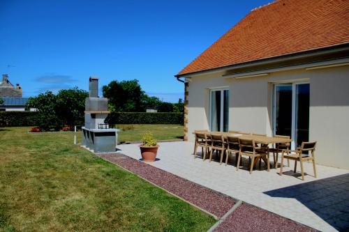a patio with a table and chairs next to a house at Villa DES COEURS NORMANDS in Pirou