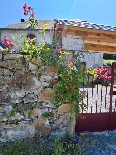 a stone wall with a gate with flowers at Gîte Chez Arnaoutou in Beaudéan