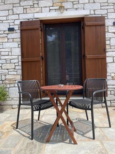 a wooden picnic table with two chairs next to a building at Pelion Roots in Zagora