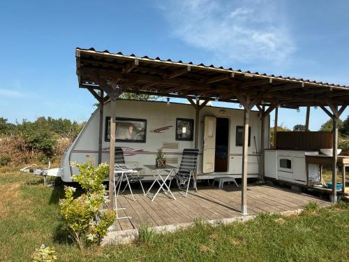 a caravan with awning and a table and chairs on a deck at Caravanne 4 Pers Vue Sur L'étang in Champsac