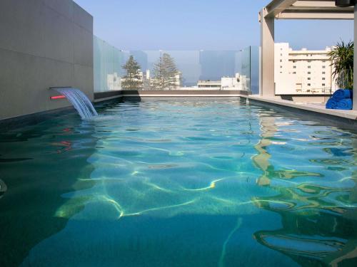 a swimming pool on the roof of a building at Mercure Larnaca Finikoudes Beach in Larnaka