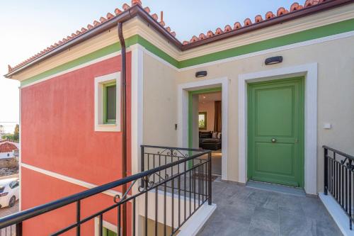 a house with a green door on a balcony at Ivy's Light in Aegina Town