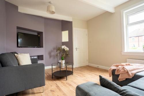 a living room with a couch and a tv on a wall at Pinkerton House in Dunfermline