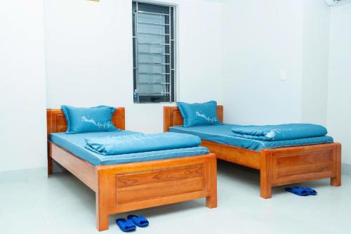 two beds with blue pillows sitting next to a window at Chị Béo ỐC in Ha Long