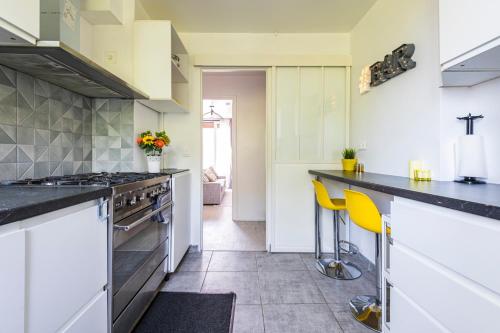 a kitchen with white cabinets and a counter with yellow chairs at Reims Centre, Appartement 4 Chambres NETFLIX in Tinqueux