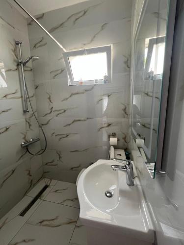 a white bathroom with a sink and a mirror at Qetësia Borsh in Borsh