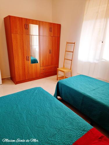 a bedroom with two beds and a cabinet and a chair at Maison Etoile de Mer in Agnone Bagni