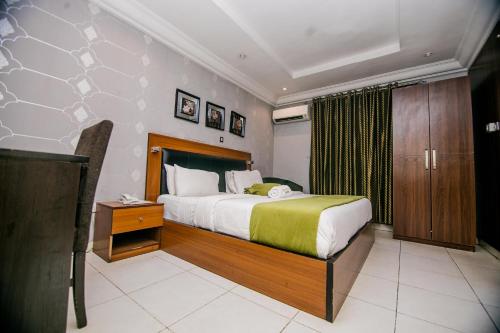 a bedroom with a large bed and a wooden cabinet at Elegance Suites Hotels in Lagos