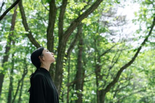 a woman standing in a forest looking up into the sky at Villa Metsä KARUIZAWA ヴィラメッサ軽井沢 in Karuizawa