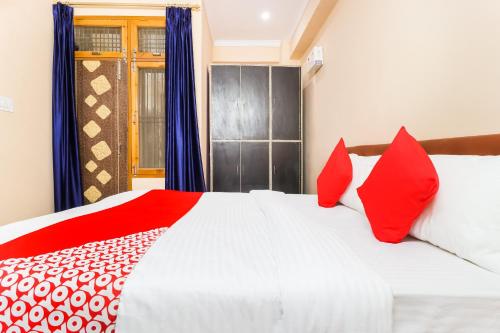a bedroom with a large white bed with red pillows at Hotel O Kalawati Palace in Lucknow