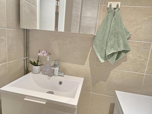 baño con lavabo blanco y toalla en Viherpihan helmi, en Espoo