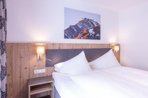 a hotel room with a bed with white sheets at Haus Sattelblick in Sankt Anton am Arlberg