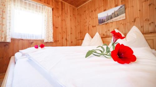 a white bed with a red flower on it at Huberbauer in Johnsbach