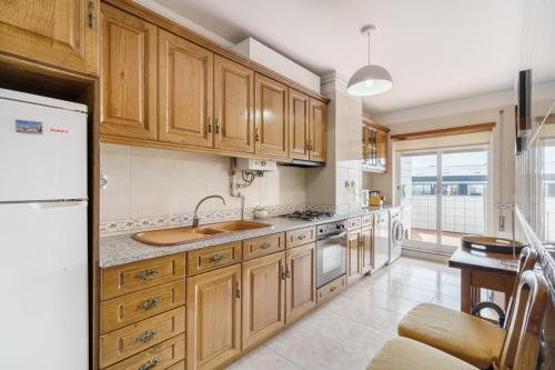 a kitchen with wooden cabinets and a white refrigerator at Ofir Beach Lodge by Minho's Guest in Fão