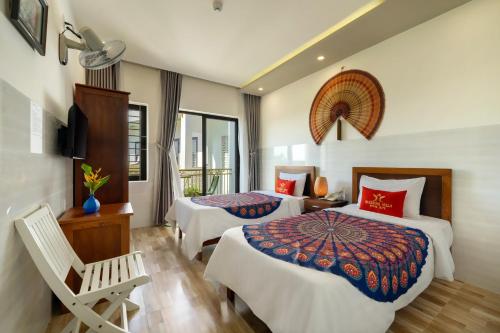 a hotel room with two beds and a chair at Blessing Villa Hoi An in Hoi An
