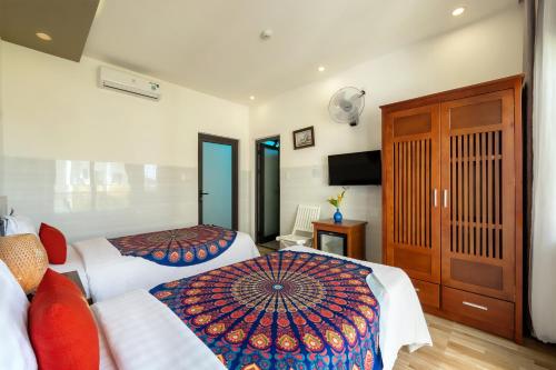 a hotel room with two beds and a television at Blessing Villa Hoi An in Hoi An