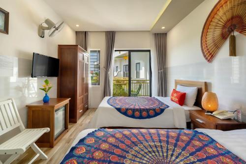 a hotel room with two beds and a television at Blessing Villa Hoi An in Hoi An