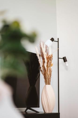 a table with a lamp and a vase with feathers at Chamalières Appartement moderne pour 5 personnes in Chamalières