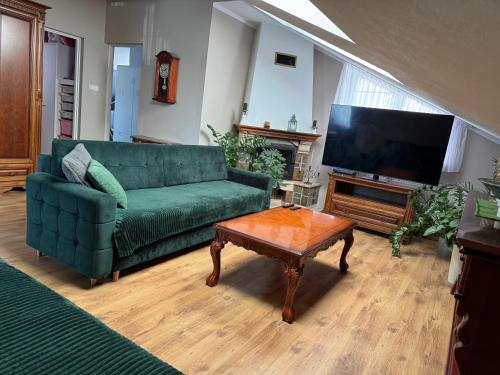 a living room with a green couch and a flat screen tv at 2 pokojowy apartament in Dąbki