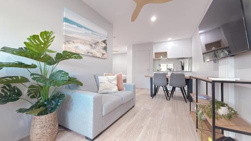 a living room with a blue couch and a kitchen at Belmoral Corporate Suites in Townsville