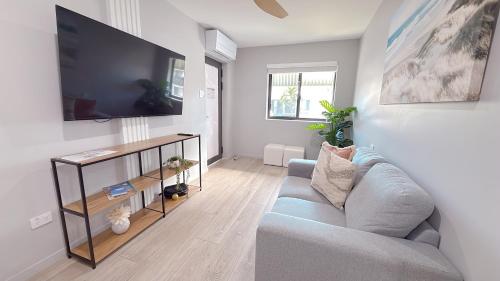 a living room with a blue couch and a flat screen tv at Belmoral Corporate Suites in Townsville