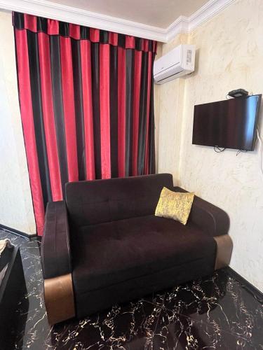 a living room with a couch and a tv at Spacious studio 5 min to the sea in Batumi