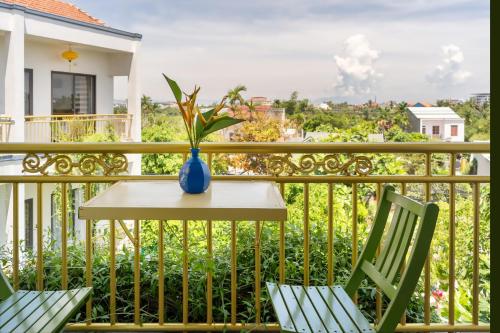 a table and chairs on a balcony with a vase at Blessing Villa Hoi An in Hoi An
