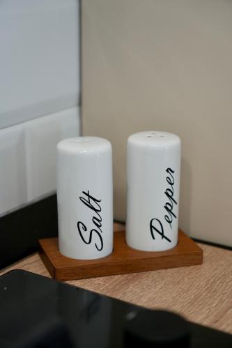 two white mugs sitting on a wooden shelf at Flat in Otopeni in Otopeni
