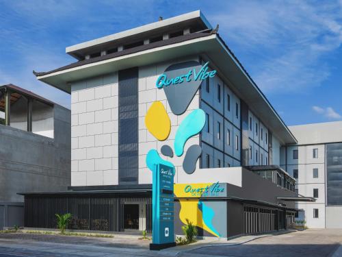 a hotel building with a sign in front of it at Quest Vibe Dewi Sri Bali in Legian