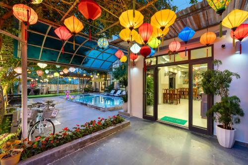 a building with a swimming pool and colorful lights at Blessing Villa Hoi An in Hoi An
