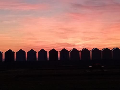 a fence with a sunset in the background at Le Nid Marin, Cayeux-sur-Mer, Baie de Somme in Cayeux-sur-Mer