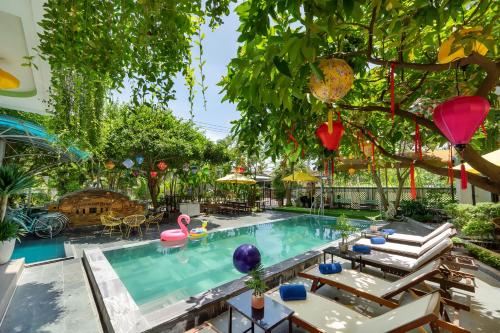 a swimming pool with chairs and a tree at Blessing Villa Hoi An in Hoi An