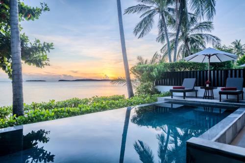 a pool with a view of the ocean at sunset at NH Collection Samui Peace Resort in Bophut