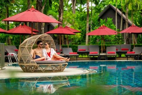 a man and a woman sitting in a chair by a pool at NH Collection Samui Peace Resort in Bophut
