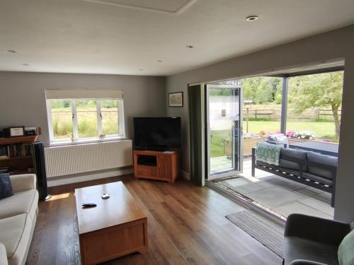 a living room with a couch and a television at Littleton Farm Barns in Saham Toney