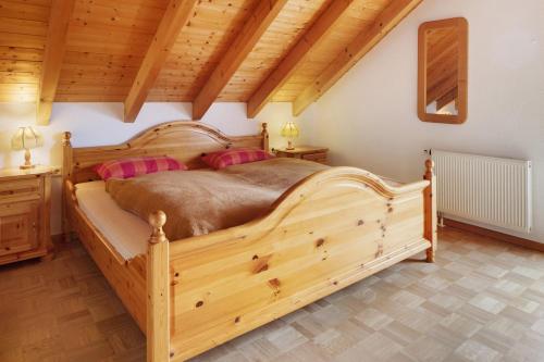 a bedroom with a large wooden bed with pink pillows at Fewo Cheny mit Hochschwarzwaldcard in Titisee-Neustadt