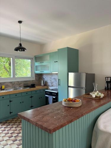 a kitchen with green cabinets and a counter with a bowl of fruit at Sunbeam house in Nea Makri