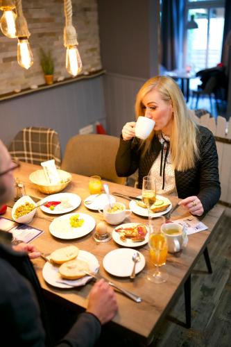 a woman sitting at a table drinking a cup of coffee at BUDE16 Boardinghouse in Norden