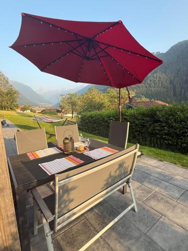 a table with a red umbrella on a patio at Haus Albuin in Sankt Gallenkirch