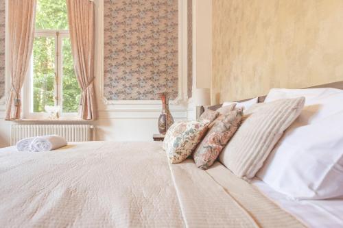 a bedroom with a white bed with pillows and a window at Villa Thor: A Majestic 100-Year-Old Manor in Genk