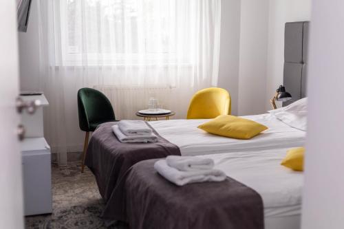 two beds in a room with two chairs and towels at Hotel Nafta Krosno in Krosno