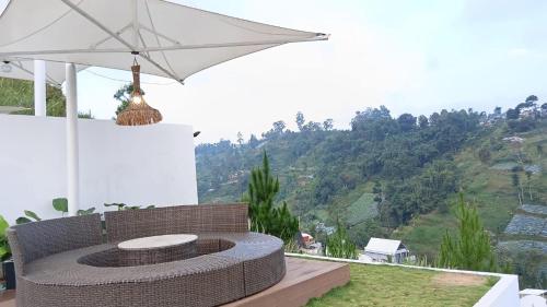 a patio with a white umbrella and a bench at Mahkota Sangkuriang Bandung in Bandung