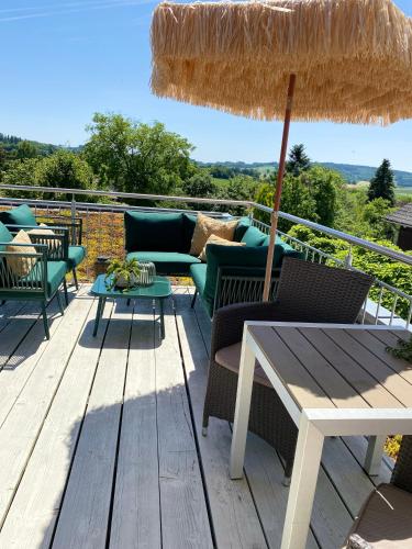 a patio with chairs and an umbrella on a deck at Moderne Ferienwohnung Nähe Bad Griesbach, Haarbach in Haarbach