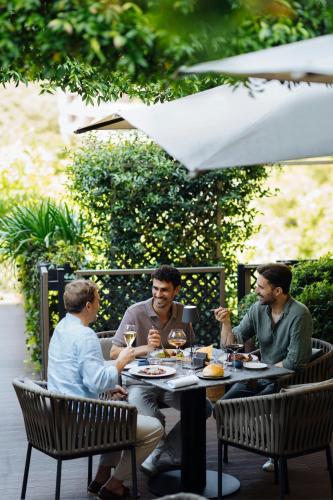 three men sitting at a table with wine glasses at The Westin Palace, Milan in Milan
