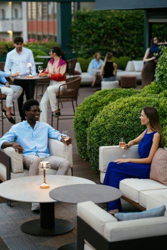 a group of people sitting in chairs on a patio at The Westin Palace, Milan in Milan